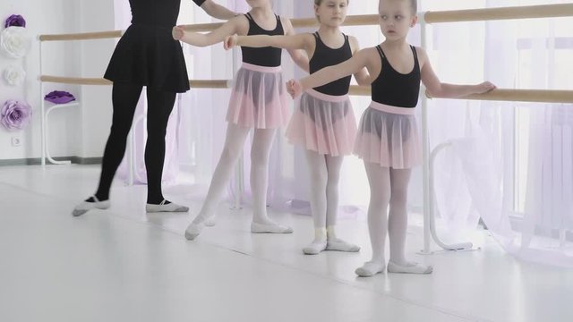 Small ballerinas are repeating the movements with the teacher. ballet lesson in the studio