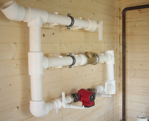 mounting of gravity heating system equipment with laser level in a boiler room. Circulation pump, stopcock, return valve, polypropylene tube and laser level