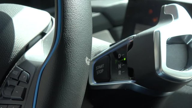 Interior view of pushing the start button of a modern electric vehicle also called an EV which uses electrically powered motors for propulsion with zero emission which does not pollute the environment