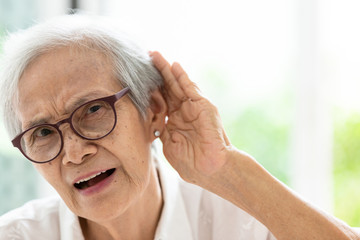 Asian senior woman listening by hand’s up to the ear,having difficulty in hearing,elderly woman hard to hear,wear glasses with hearing impairment,hearing impaired old people