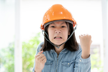 Angry asian little girl hand with fist gesture with safety helmet or hard hat,closeup portrait of cute child shows fist,having emotions,feelings,aggression concept