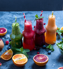 Colorful detox smoothie in bottles, summer diet fresh drink, red, green, yellow smoothie with...