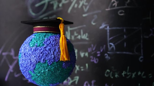 Education world, study learning achievement success in abroad global ideas. Rotating Graduation cap on models paper earth globe on formula equation blackboard background. Congratulation in university
