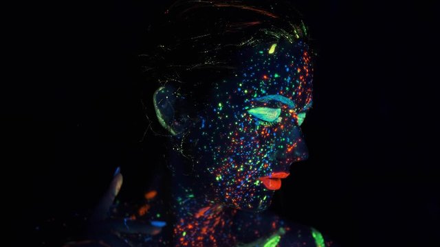 Fashion model woman in neon lights posing in studio, portrait of beautiful girl,. face painted with glow in the dark paint.