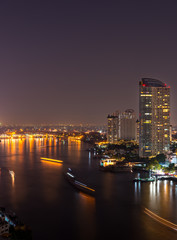 Fototapeta na wymiar The Chao Phraya River in Bangkok, at night. Illuminated windows in the houses along the river.