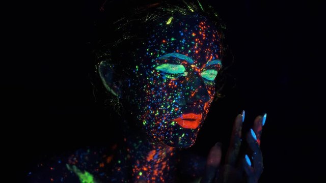 Fashion model woman in neon light, fluorescent make-up. portrait of a girl in the neon light. face painted with glow in the dark paint.