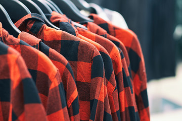 Men red plaid shirt on hangers in a retail clothes store.