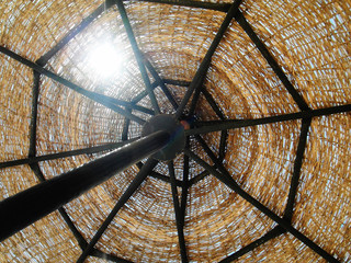 The wicker sun umbrella on the blue sky background. Contre. Closeup