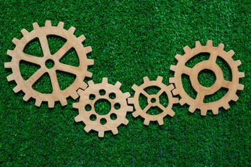 wooden gears on a background of artificial green grass. the mechanism of the business vision.
