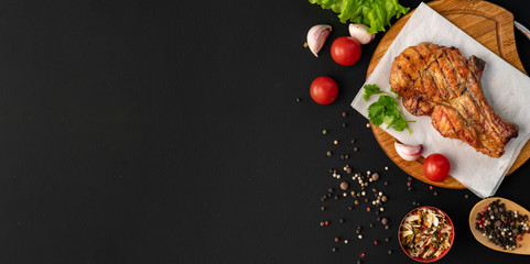 grilled meat copy space, dark surface, herbs, lettuce, tomato , black spice in the wooden spoons