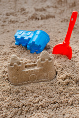 Fototapeta na wymiar Children toys for build the sandcastle, Shovel, Molds laying on the sand at the seashore,