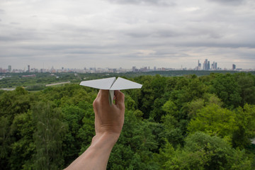 Human hand holding paper plane against Moscow cityscape