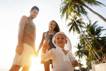 family in love on the beach with son are playing at sunset.