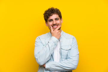 Obraz premium Blonde man over isolated yellow wall laughing
