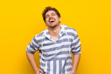 Obraz premium Blonde man over yellow wall happy and smiling