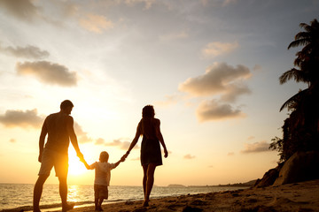 Fototapeta premium family walk along the beach at sunset with his son: back view silhouette