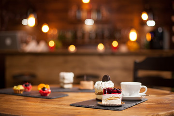 Composition of different cakes with tasty flavours over a wooden table in a coffee shop