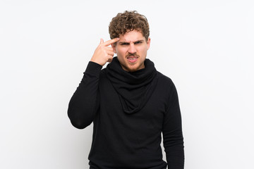 Blonde man over isolated white wall making the gesture of madness putting finger on the head