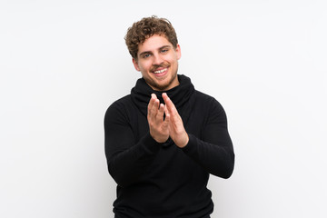 Blonde man over isolated white wall applauding after presentation in a conference