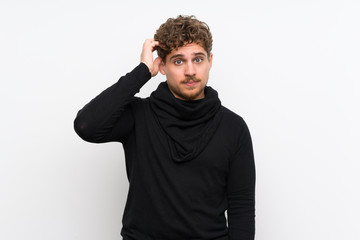 Blonde man over isolated white wall with an expression of frustration and not understanding