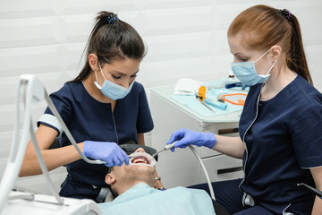 Girl dentist treats the patient. Doctor treats tooth pain at the dentist's office.