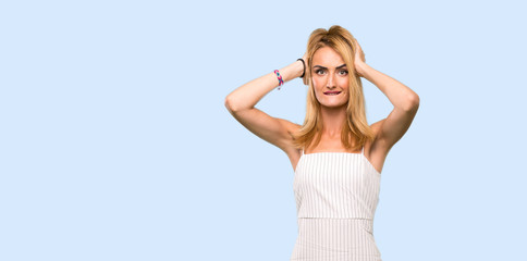 Fototapeta na wymiar Young blonde woman frustrated and takes hands on head over isolated blue background