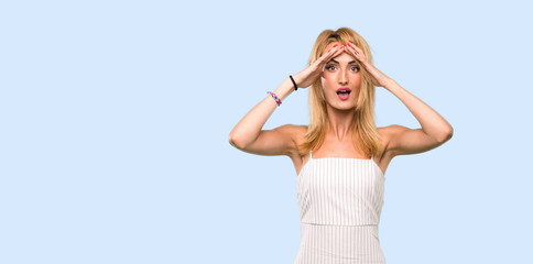 Young blonde woman with surprise expression over isolated blue background