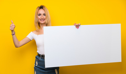 Fototapeta na wymiar Young blonde woman over isolated yellow wall holding an empty white placard for insert a concept