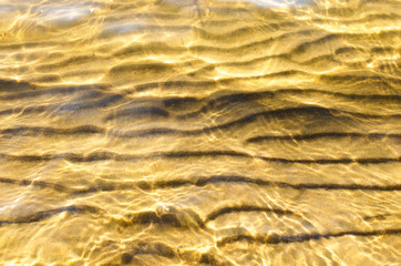 Sandy lake bottom in crystal clear water in summer on a bright Sunny day.