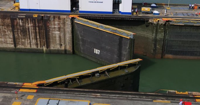 Panama City canal gates closing workers. Lifts a ship between the Atlantic and Pacific Ocean. 52 miles long. Tug boats electric trains pull cargo, cruise, oil, container, bulk, ships. 14,000 ships ann