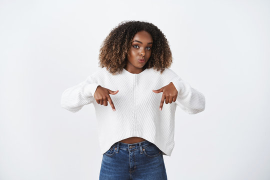I sure you like it, look. Portrait of enthusiastic and amused cute cheeky girlfriend pointing down and hinting to gaze downwards at awesome super promotion over white background