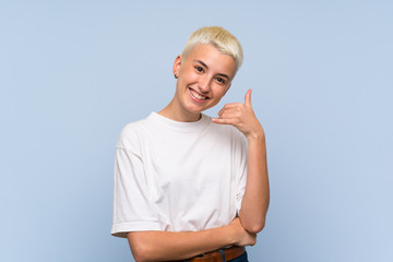 Teenager girl with white short hair over blue wall making phone gesture. Call me back sign