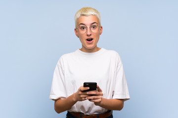 Fototapeta premium Teenager girl with white short hair over blue wall surprised and sending a message