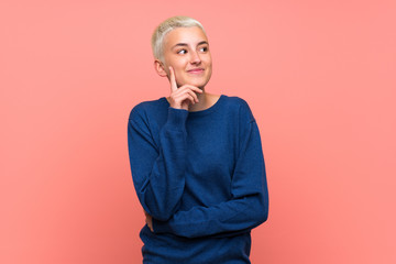 Teenager girl with white short hair over pink wall thinking an idea while looking up