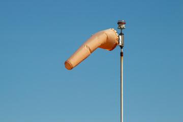 Windsock indicating wind direction and relative speed on blue sky background