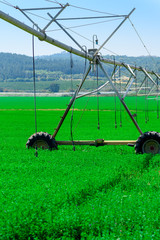 Center pivot sprinkler system watering plants in a green field.