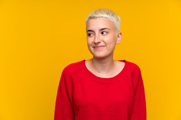 Teenager girl with white short hair over yellow wall standing and looking to the side