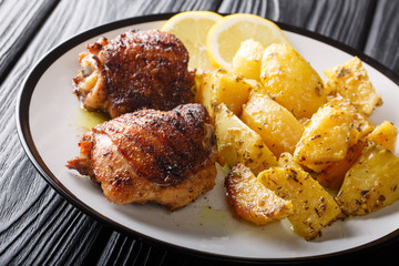 Greek lemon potatoes with garlic and herbs served with chicken thigh grilled close-up. horizontal
