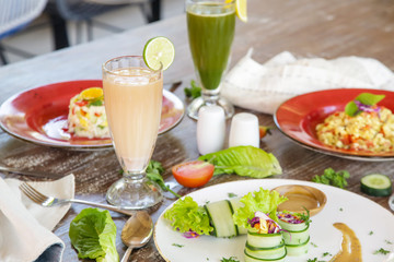 Healthy organic vegetarian dishes and glasses of detox drinks served on the restaurant table. 