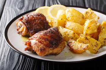 Main course: grilled chicken thighs served with delicious lemon garlic potatoes closeup. horizontal