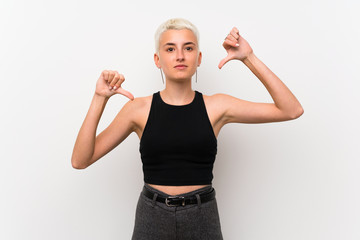 Teenager girl with short hair over white wall showing thumb down