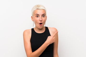 Teenager girl with short hair over white wall surprised and pointing side