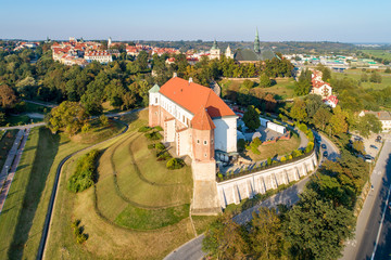 Naklejka premium Sandomierz, Poland. Medieval castle in front, old town with town hall tower and gothic cathedral in the background. Aerial view in sunset light
