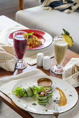 Healthy organic vegetarian dishes and glasses of detox drinks served on the restaurant table. 