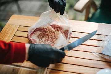 person opening plastic bag with kobe steak inside