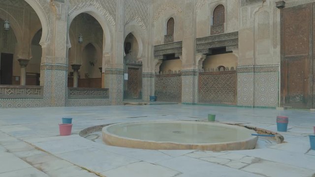 Panning around inside the Hassan ii Mosque square where a water fountain is being constructed with stone and concrete in courtyard with archways and large doors