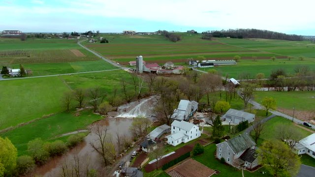 Aerial view of rapids on a small river and a covered bridge in the American countryside, farms, houses on the banks, Conestoga river and Bitzer's Mill covered bridge in Lancaster County, Pennsylvania
