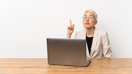 Teenager girl with short hair with a laptop intending to realizes the solution while lifting a finger up