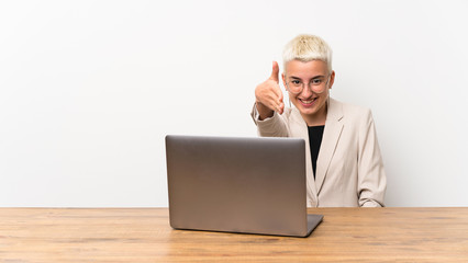 Teenager girl with short hair with a laptop shaking hands for closing a good deal
