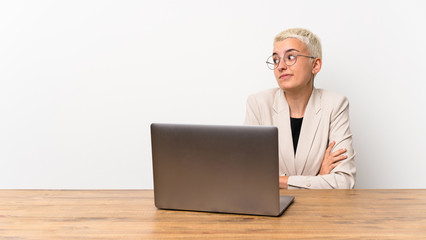 Teenager girl with short hair with a laptop making doubts gesture while lifting the shoulders